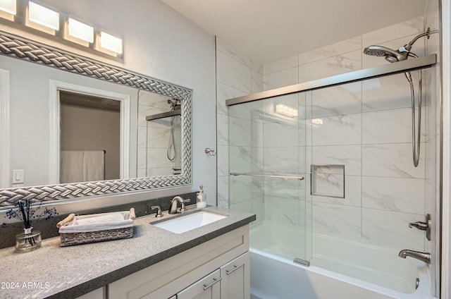 bathroom featuring combined bath / shower with glass door and vanity