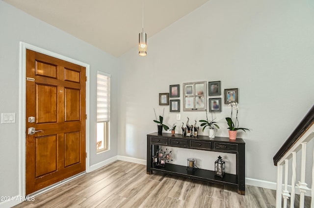 foyer with light hardwood / wood-style floors and vaulted ceiling