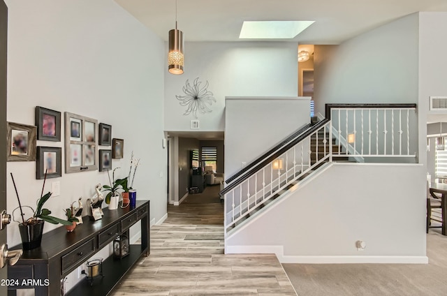 stairway featuring a high ceiling, a skylight, and hardwood / wood-style floors