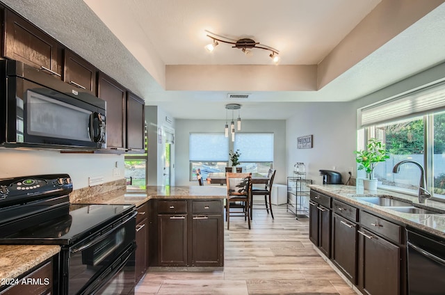 kitchen featuring black appliances, light wood-type flooring, dark brown cabinetry, sink, and decorative light fixtures