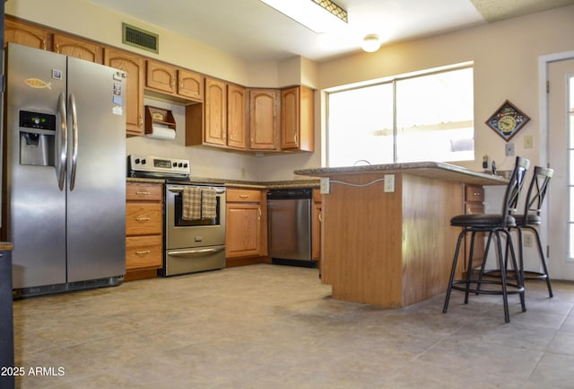 3519 W Libby St, Glendale, AZ 85308 - kitchen with stainless steel appliances, plenty of natural light, dark countertops, and a breakfast bar area