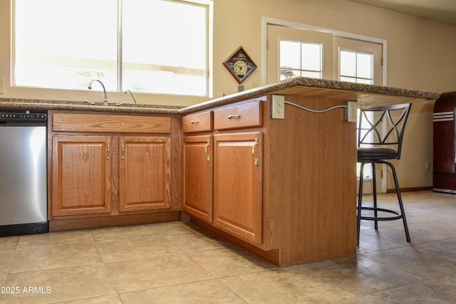 3519 W Libby St, Glendale, AZ 85308 - kitchen with stainless steel dishwasher, a kitchen breakfast bar, brown cabinets, light tile patterned flooring, and a sink