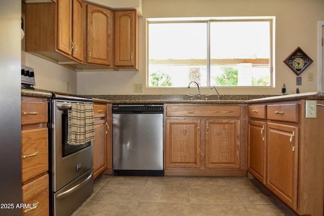 3519 W Libby St, Glendale, AZ 85308 - kitchen with appliances with stainless steel finishes, brown cabinets, dark countertops, and light tile patterned floors