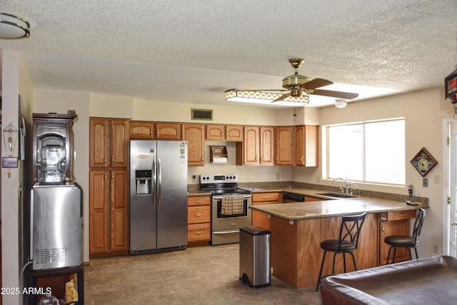 3519 W Libby St, Glendale, AZ 85308 - kitchen with stainless steel appliances, a peninsula, a ceiling fan, brown cabinetry, and a sink