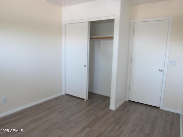 unfurnished bedroom with a closet, baseboards, and wood finished floors