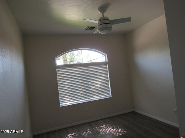 empty room with baseboards, ceiling fan, visible vents, and wood finished floors