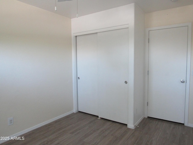 unfurnished bedroom featuring a closet, baseboards, and wood finished floors