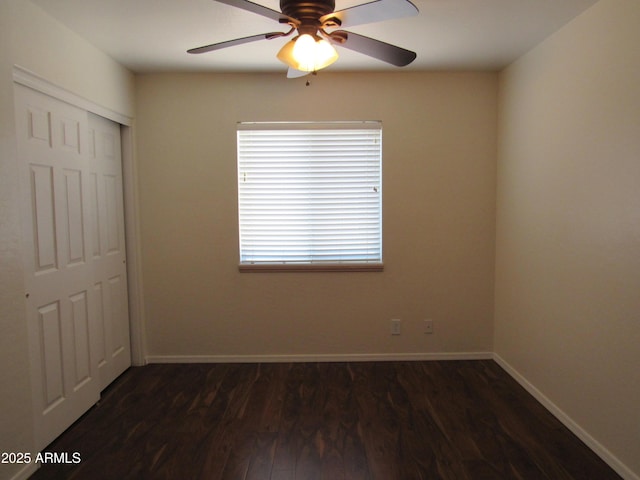 empty room featuring dark wood-style floors, baseboards, and a ceiling fan