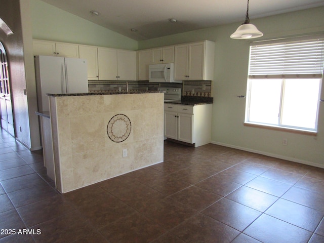 kitchen with lofted ceiling, white microwave, dark tile patterned floors, white cabinetry, and dark stone counters