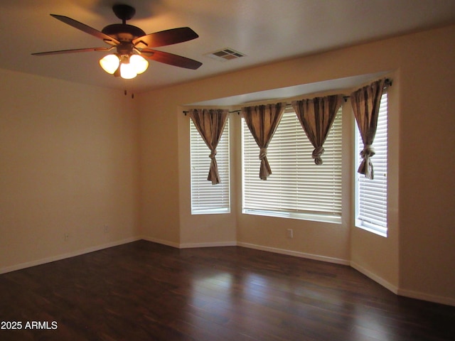 empty room with a wealth of natural light, visible vents, and wood finished floors