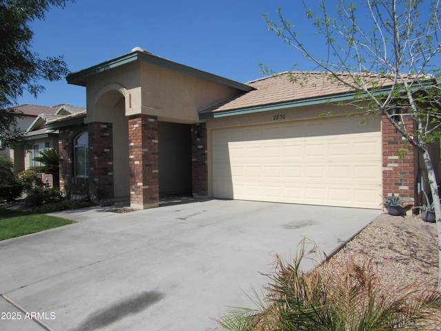 view of front facade featuring concrete driveway, brick siding, an attached garage, and stucco siding