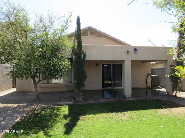 rear view of house with central AC unit, a lawn, fence, and stucco siding