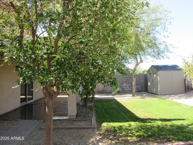 view of yard featuring fence, a storage unit, and an outdoor structure