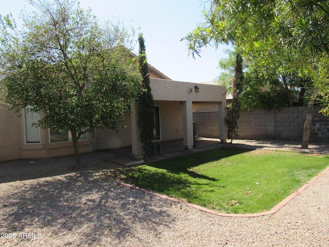 exterior space with a patio, stucco siding, a lawn, fence, and a garage