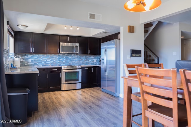 kitchen featuring sink, appliances with stainless steel finishes, tasteful backsplash, dark brown cabinetry, and light wood-type flooring