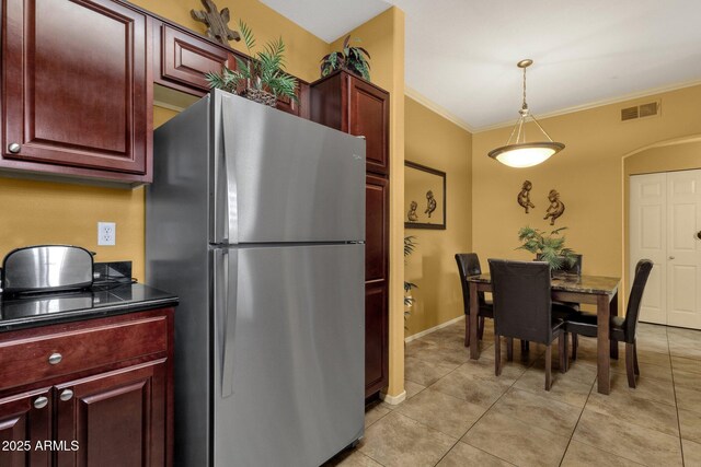 5335 E Shea Blvd Unit 1094, Scottsdale, AZ 85254 - kitchen with freestanding refrigerator, reddish brown cabinets, dark countertops, crown molding, and light tile patterned floors