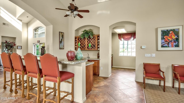 5335 E Shea Blvd Unit 1094, Scottsdale, AZ 85254 - kitchen featuring a breakfast bar area, ceiling fan, high vaulted ceiling, brown cabinets, and baseboards