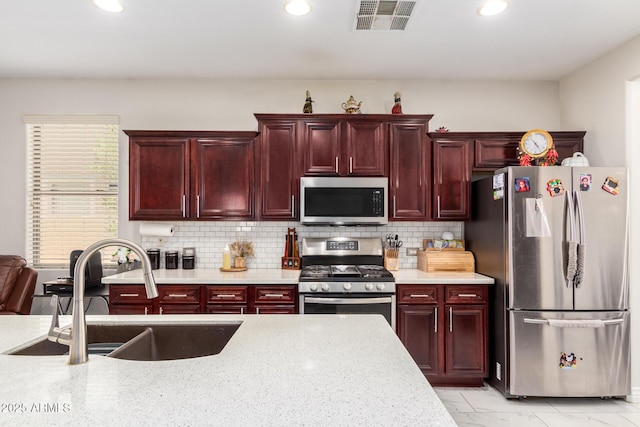 205 N 107th Dr, Avondale, AZ 85323 - kitchen with appliances with stainless steel finishes, reddish brown cabinets, recessed lighting, decorative backsplash, and light marble finish flooring