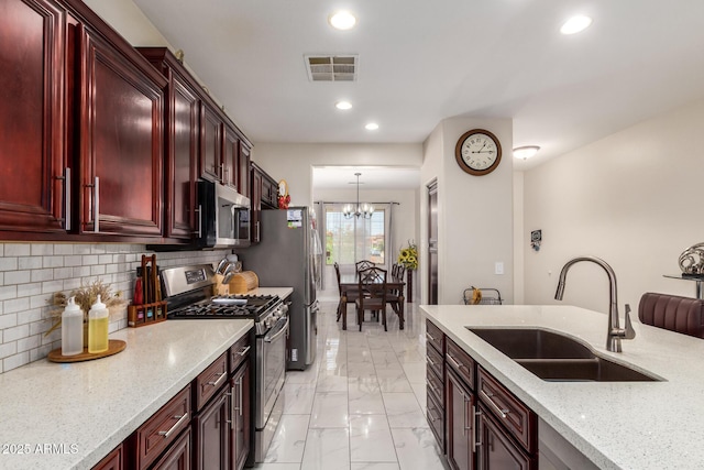 205 N 107th Dr, Avondale, AZ 85323 - kitchen featuring appliances with stainless steel finishes, dark brown cabinets, a chandelier, light marble finish flooring, and recessed lighting