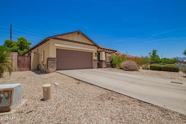 205 N 107th Dr, Avondale, AZ 85323 - view of front of home with a gate, stone siding, an attached garage, and concrete driveway