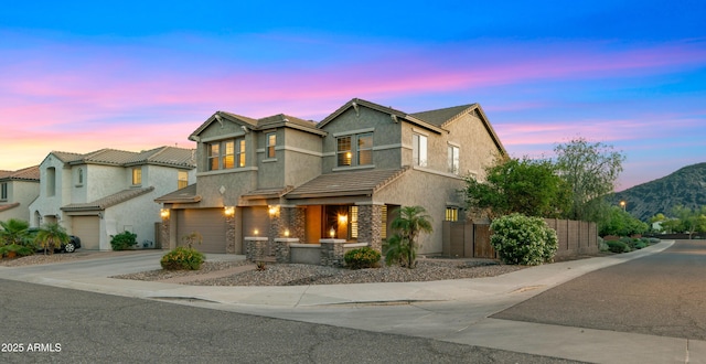 view of front of home with stucco siding, a garage, fence, and concrete driveway