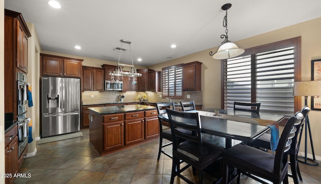 kitchen featuring decorative backsplash, a kitchen island, visible vents, dark countertops, and stainless steel appliances