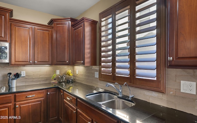 kitchen featuring a sink, dark countertops, tasteful backsplash, and stainless steel microwave