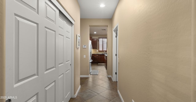 hall with dark tile patterned floors, baseboards, and recessed lighting