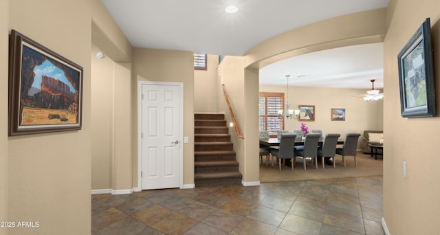 stairway with baseboards, arched walkways, and a notable chandelier