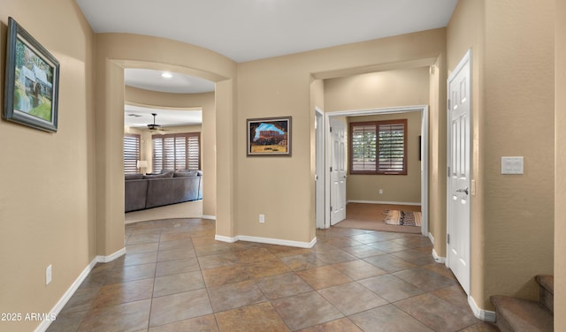 entryway with baseboards, ceiling fan, and stairs