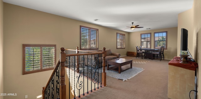 carpeted living area featuring visible vents, baseboards, and ceiling fan