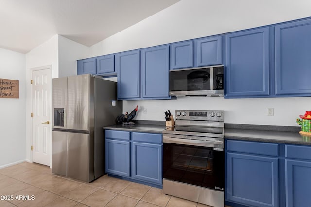 kitchen with dark countertops, light tile patterned floors, blue cabinetry, and appliances with stainless steel finishes