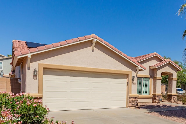 view of front of house featuring a tile roof, concrete driveway, stucco siding, stone siding, and an attached garage