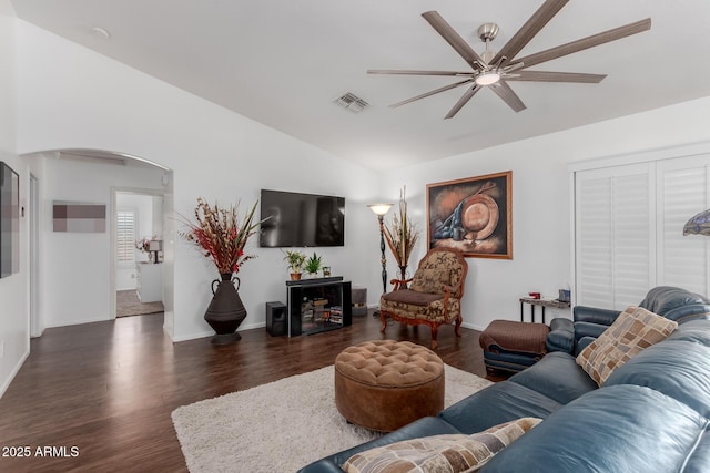 living room featuring visible vents, vaulted ceiling, wood finished floors, arched walkways, and a ceiling fan