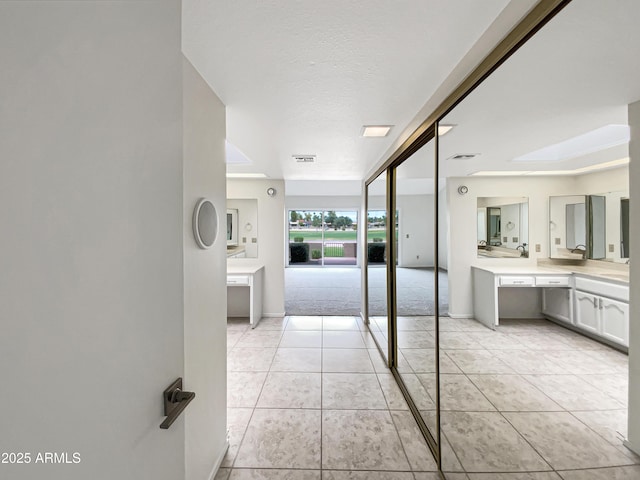 full bathroom featuring vanity, baseboards, tile patterned floors, a skylight, and visible vents