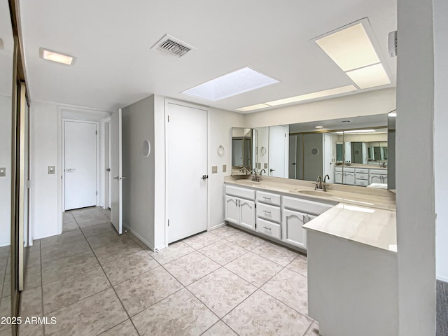 bathroom with tile patterned flooring, a sink, a skylight, visible vents, and double vanity