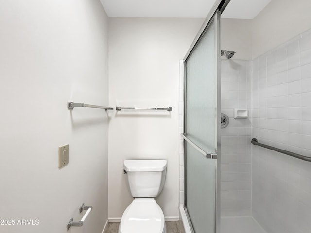 full bath with baseboards, toilet, and a stall shower