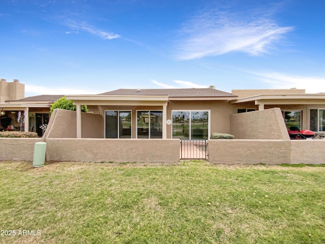 back of property with a lawn, stucco siding, and fence