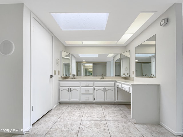 bathroom featuring double vanity, a sink, a skylight, and tile patterned flooring