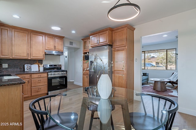 kitchen with backsplash, decorative light fixtures, light hardwood / wood-style flooring, and stainless steel appliances