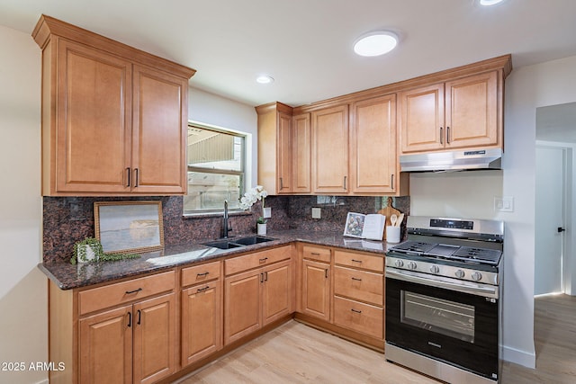 kitchen with gas range, sink, decorative backsplash, and dark stone counters