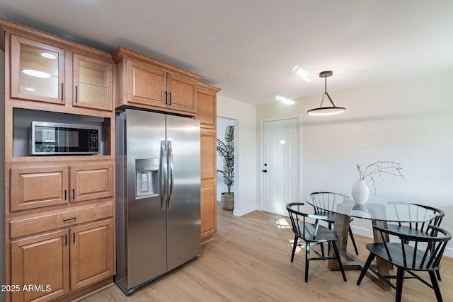 kitchen with pendant lighting, stainless steel appliances, and light hardwood / wood-style floors