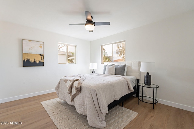 bedroom with ceiling fan, multiple windows, and light hardwood / wood-style flooring