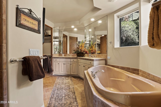 bathroom featuring vanity, a relaxing tiled tub, and tile patterned floors