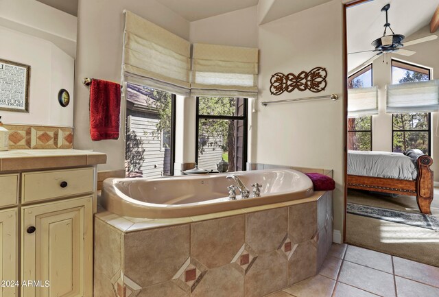 bathroom with ceiling fan, tile patterned floors, tiled tub, lofted ceiling, and vanity