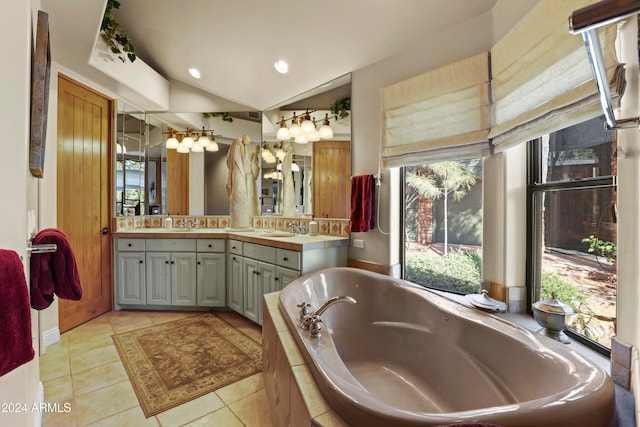 bathroom featuring tile patterned floors, tiled tub, vanity, and lofted ceiling