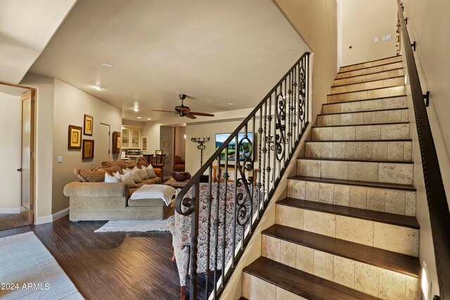 staircase with hardwood / wood-style floors and ceiling fan