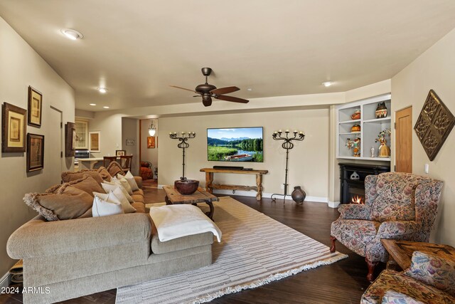 living room featuring ceiling fan and dark wood-type flooring