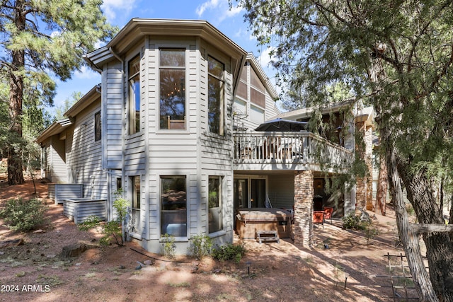 back of property featuring a deck, a hot tub, and a patio area