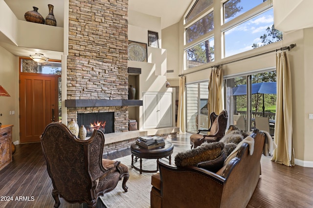 living room with a stone fireplace, a towering ceiling, and dark hardwood / wood-style floors